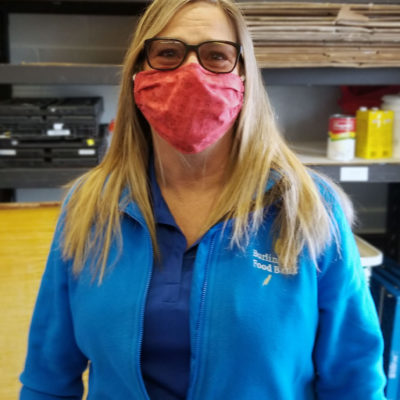 A photo portrait of a woman wearing a mask and a Burlington Food Banks sweater