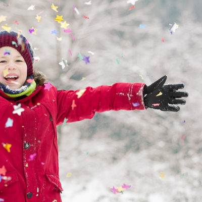 A child throwing confetti in the snow