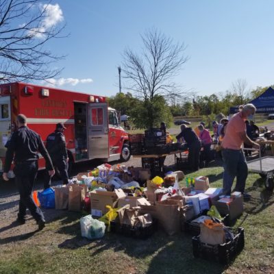 A picture of civilians and first responders setting up tables of fresh produce outdoors