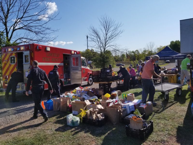 A picture of civilians and first responders setting up tables of fresh produce outdoors