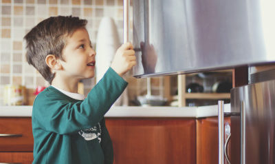A picture of a boy looking inside a refrigerator