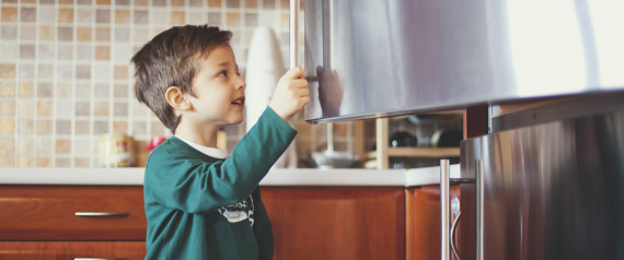A picture of a boy looking inside a refrigerator