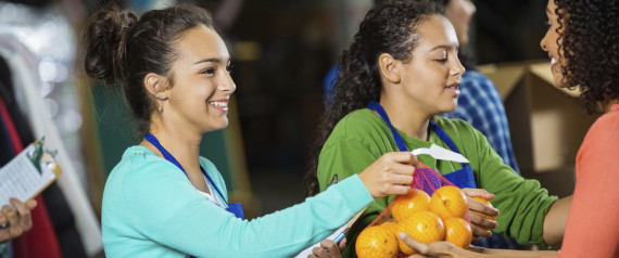 A picture of a woman handing a bag of oranges to another woman