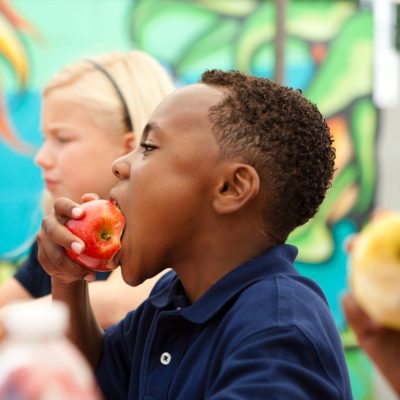 A picture of a girl and two boys eating apples