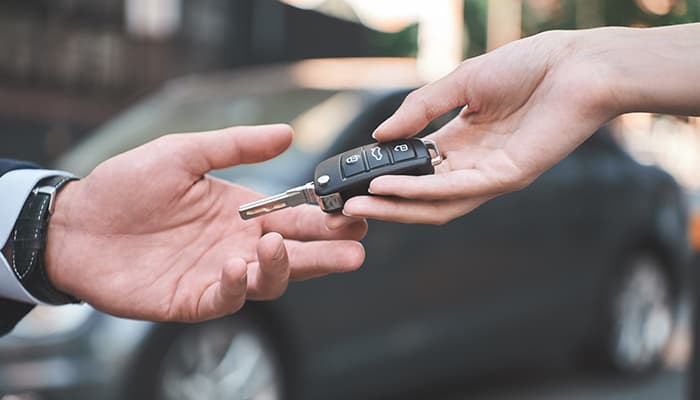 One person's hand passing a set of car keys to another hand.