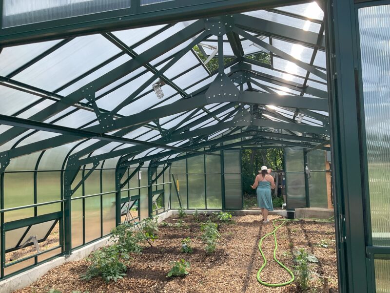 A woman walking through a greenhouse at a food bank.