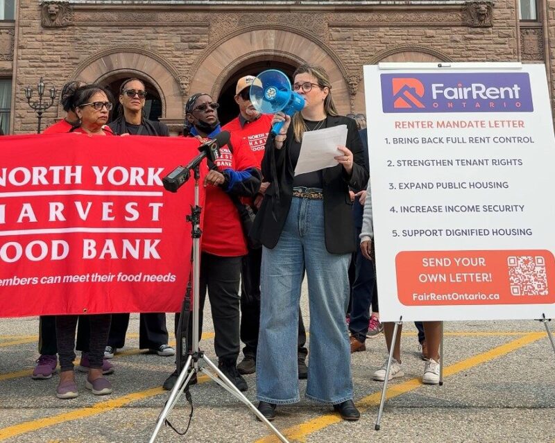 A woman stands with a megaphone advocating for affordable housing.