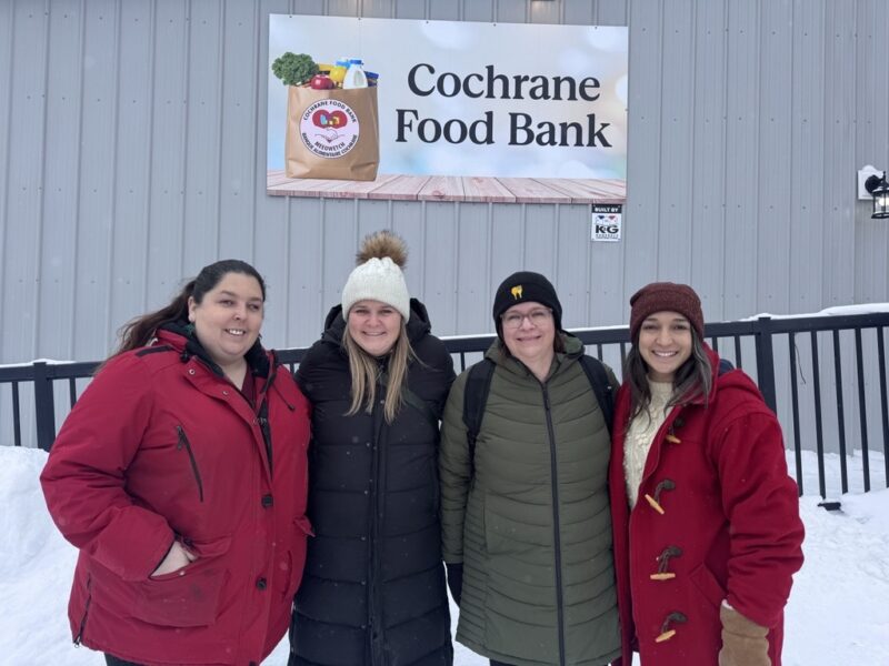 Quatre personnes se tiennent devant le nouvel entrepôt de la banque alimentaire Cochrane.