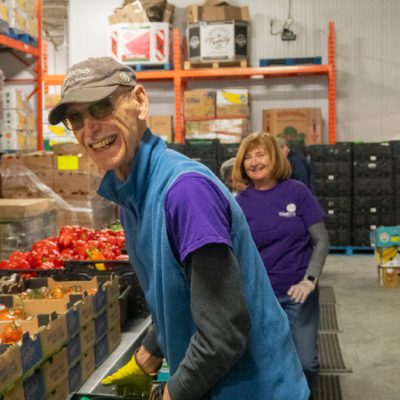 A volunteer sorting vegetables at a food bank smiles.