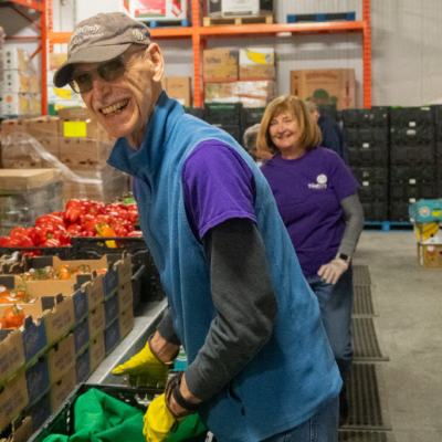 Une bénévole triant des légumes dans une banque alimentaire sourit.