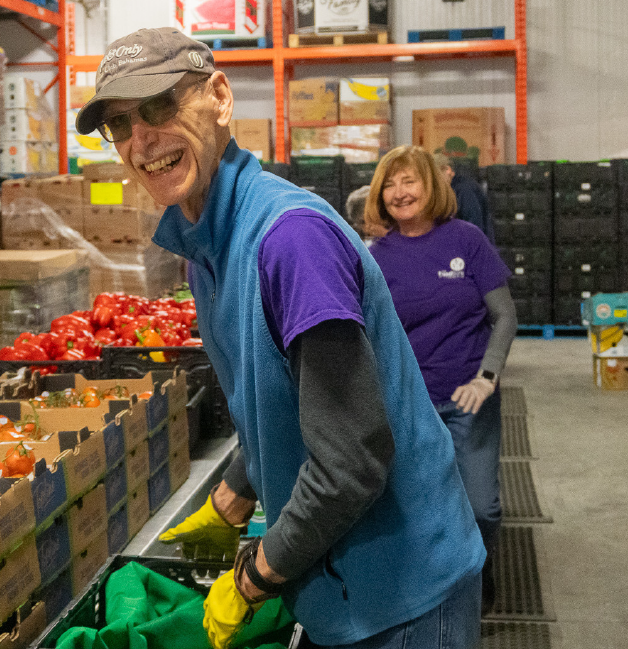 A volunteer sorting vegetables at a food bank smiles.