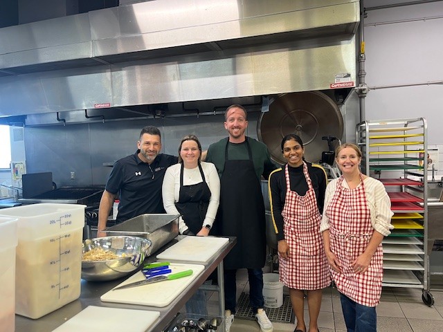 A group of people smiling and wearing aprons.