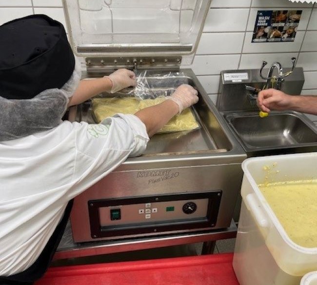 A person using a vacuum sealer to prepare soup made through our Farm to Food Program for sharing across the province.