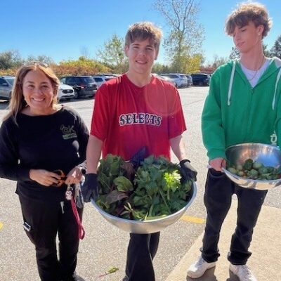 Two young men holding bowls of lettuce and brussel sprouts