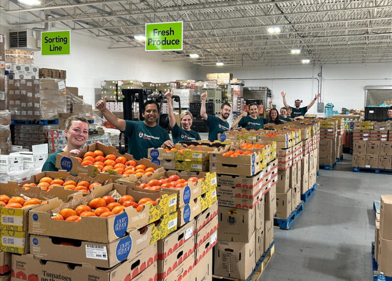 A group of people standing in front of pallets of fresh produce.