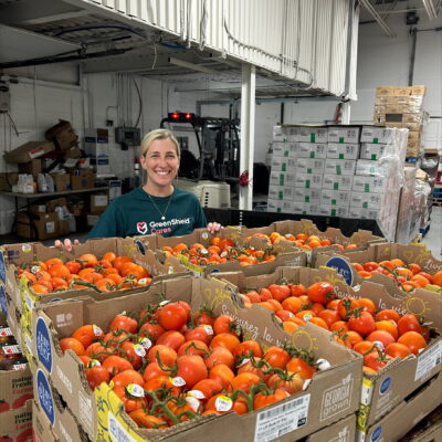 Une femme se tient derrière une palette d'oranges fraîches.