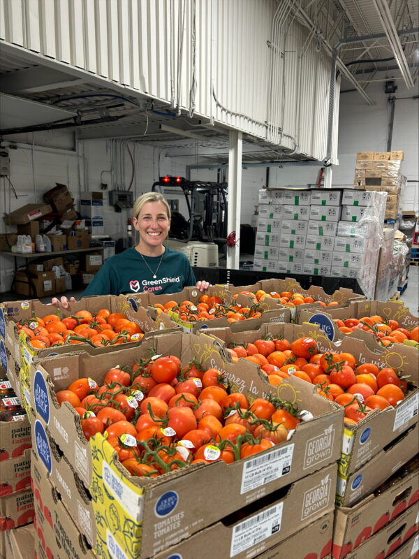 Une femme se tient derrière une palette d'oranges fraîches.