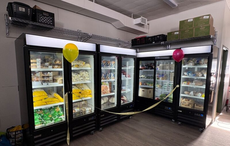 Deux réfrigérateurs et congélateurs à portes vitrées, décorés de ballons et de banderoles.