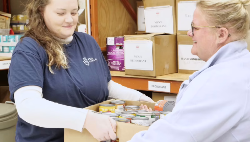A Feed Ontario employee passes a box to another woman.