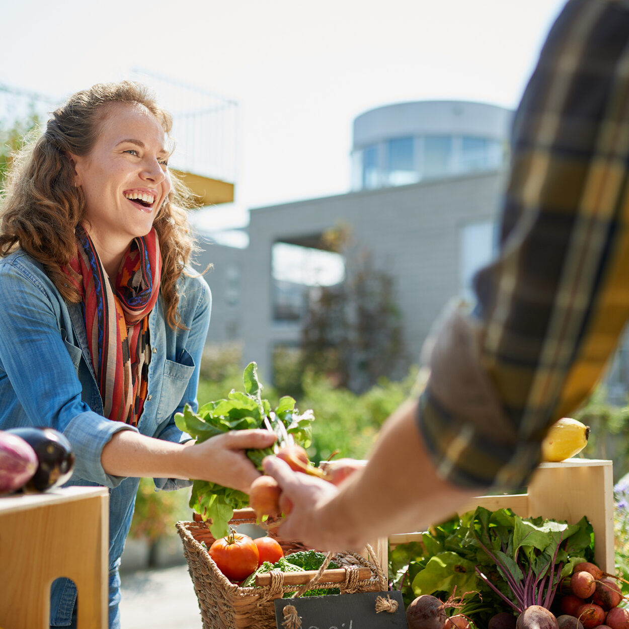 A picture of a smiling woman handing a bunch of radishes to another person off camera